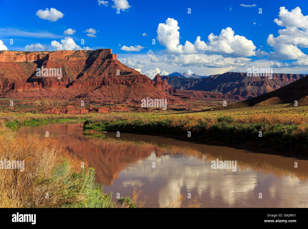This view looks down the Colorado River toward a red rock butte from which Fisher Towers are emerging (right). Stock Photo