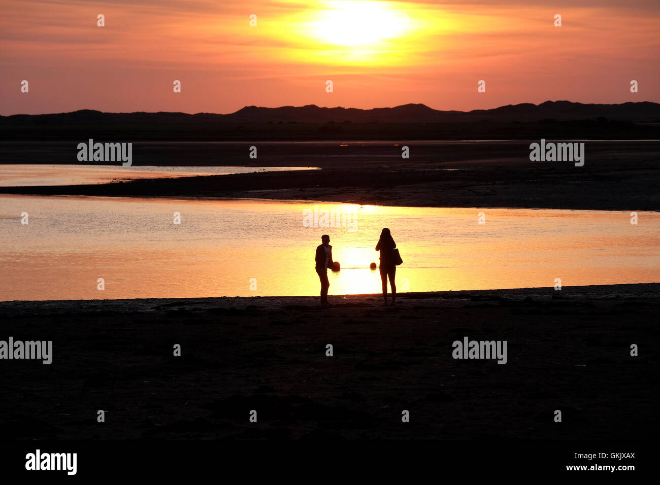 two people on beach at sunset in silhouette Stock Photo - Alamy