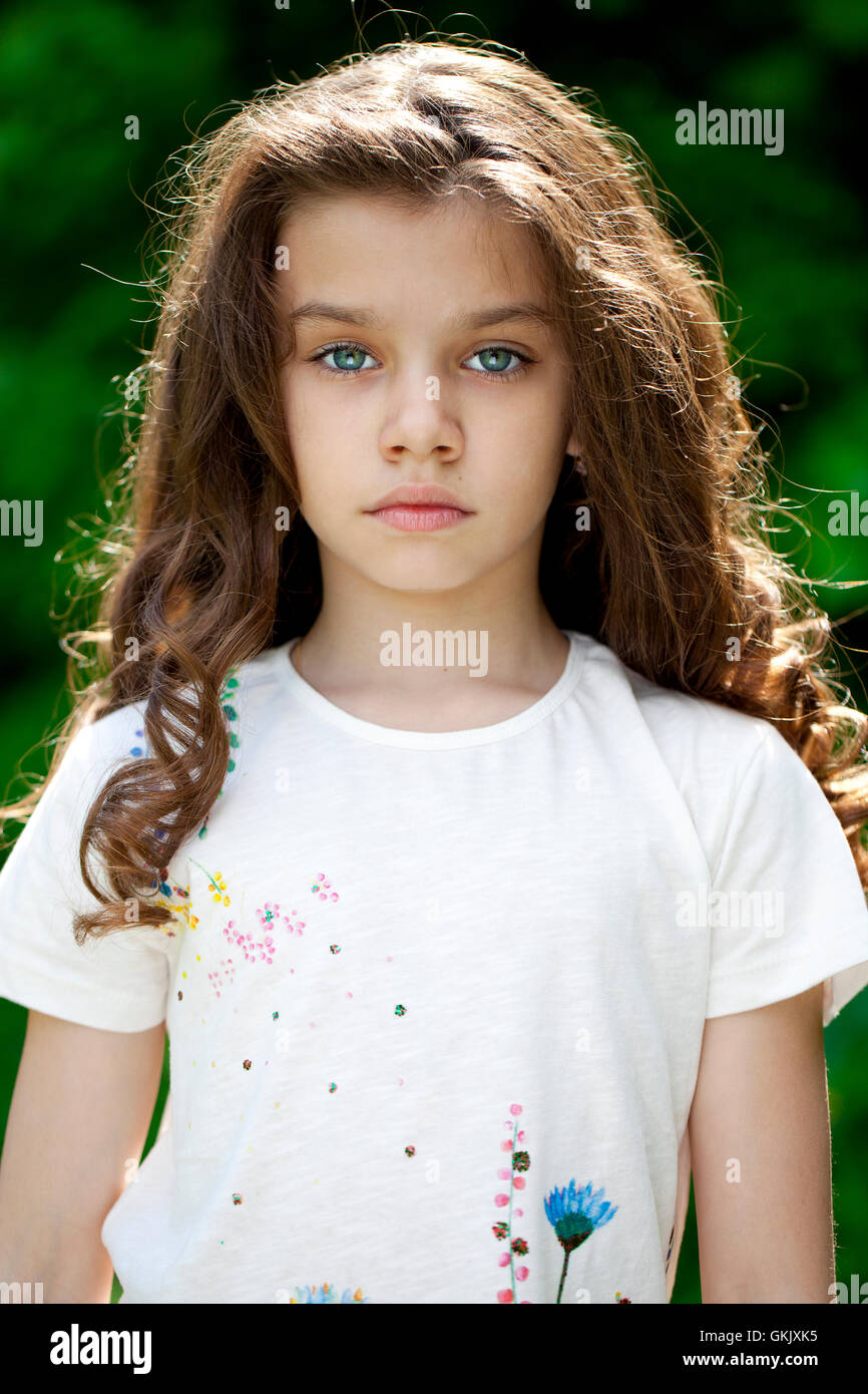 Portrait of a beautiful young little girl on the background of summer ...