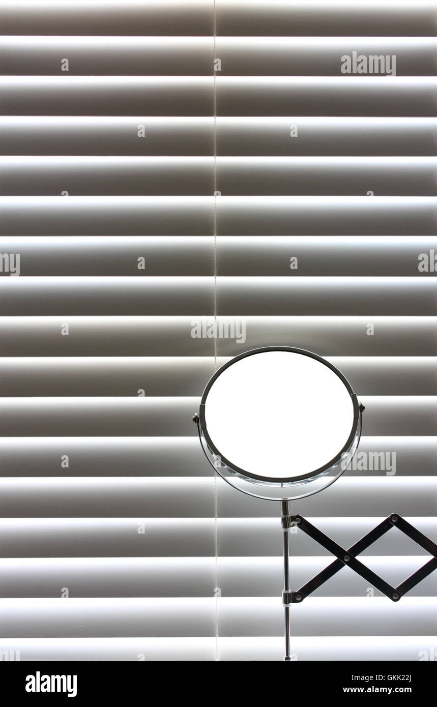 Bathroom mirror in front of blinds with sun coming though Stock Photo