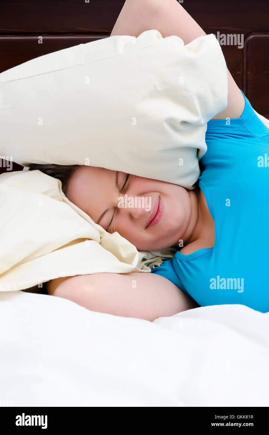 Young woman covering ears with pillow because of noise Stock Photo Alamy