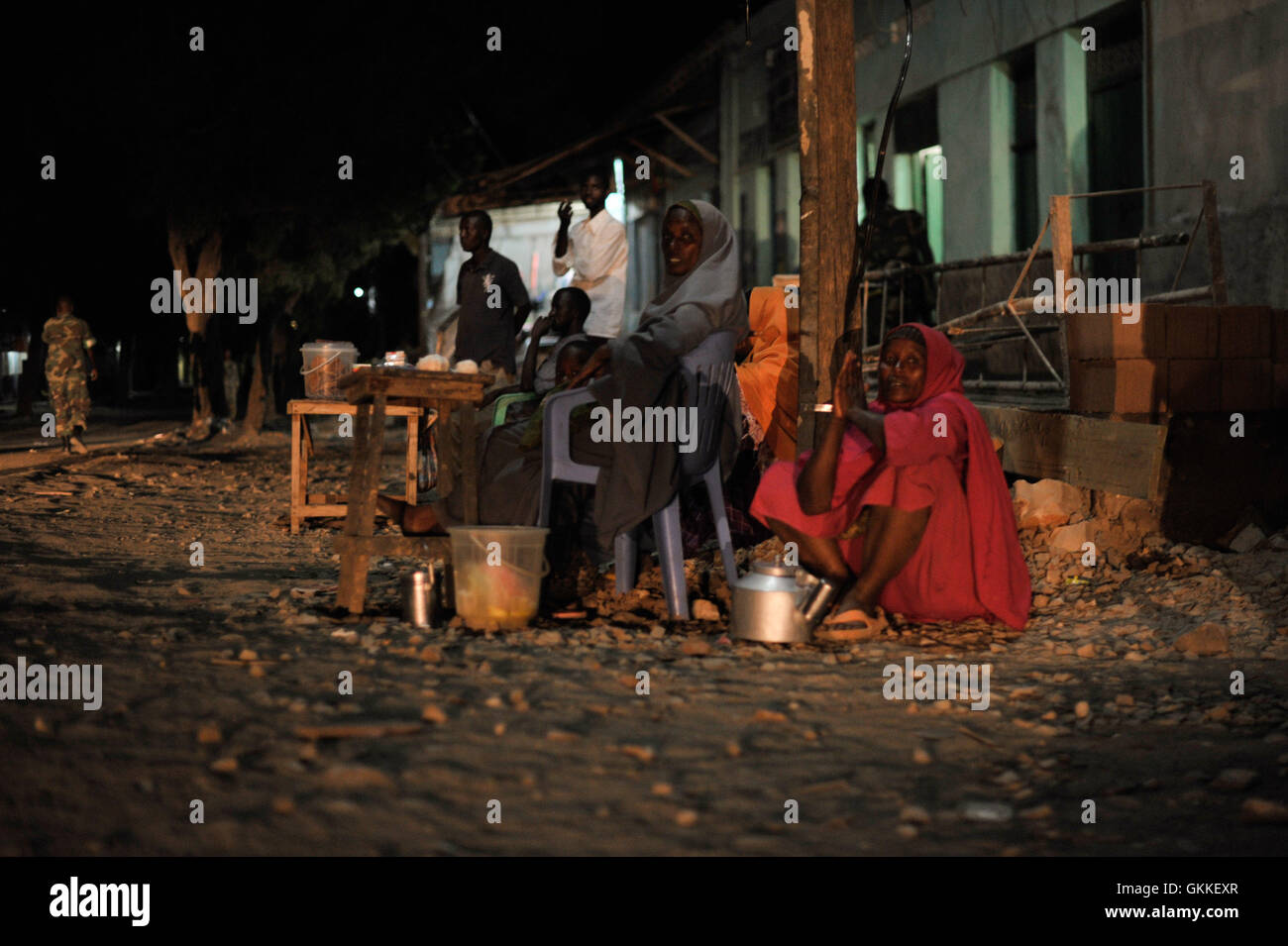 Somali women sell tea on the side of the road in Baidoa, while Ethiopian soldiers as part of the African Union Mission in Somalia, conduct a night patrol through the city on June 22. AMISOM Photo / Tobin Jones Stock Photo