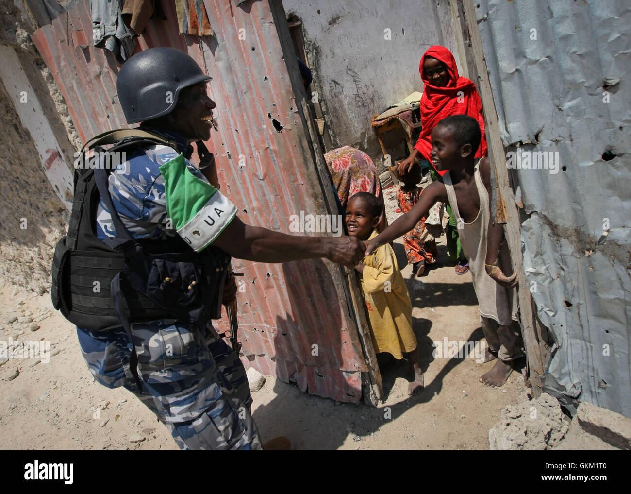 SOMALIA, Mogadishu: In a handout photo taken and released by the African Union-United Nations Information Support Team 09 November, a Ugandan police officer serving as part of a Formed Police Unit (FPU) with the African Union Union Mission in Somalia (AMISOM) shakes hands with a young Somali boy during a foot patrol in the Kaa'ran district of the Somali capital Mogadishu. AMISOM's FPUs are working with their counterparts in the Somali Police Force (SPF) in helping to provide security in Mogadishu in addition to training and mentoring the SPF on policing techniques and practises. AU-UN IST PHOT Stock Photo