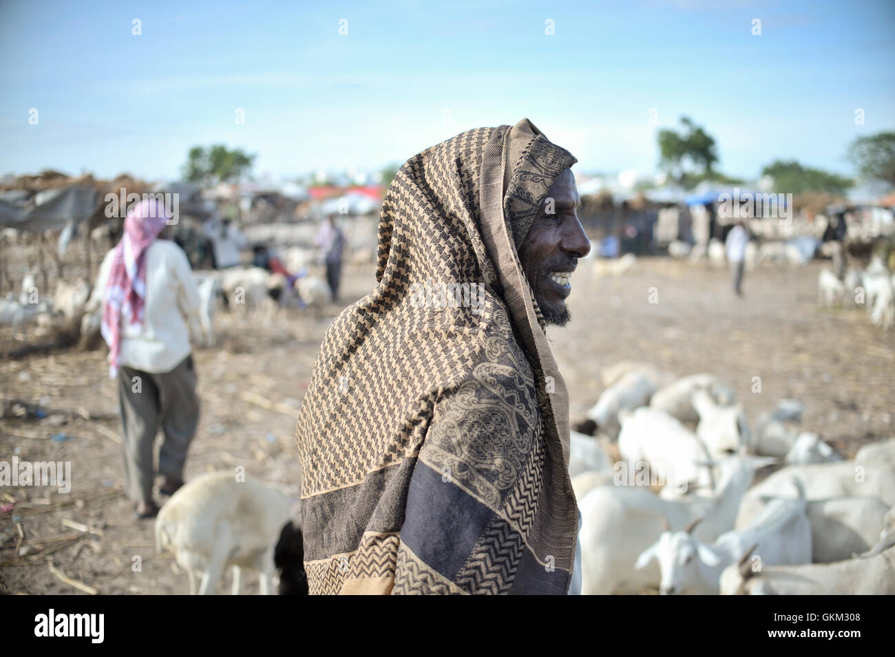 A Somali man stands next to his herd of goats at Bakara Animal Market in Mogadishu, Somalia, on April 13. Once notorious for being both the site of Black Hawk Down, in which 18 American soldiers were killed in 1993, and later as an al-Shabaab stronghold, Bakara market is now slowly losing its past notoriety and becoming better known for its thriving economy. In the district's animal market, thousands of goats are now brought each morning, where they are sold on to later be slaughtered for their meat. AU UN IST PHOTO / TOBIN JONES. Stock Photo