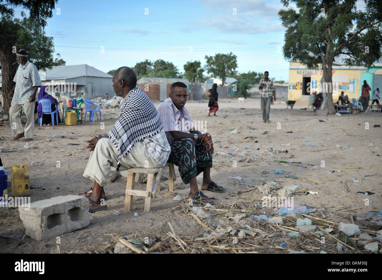 Two men sit near Bakara Animal Market in Mogadishu, Somalia, on April 13. Once notorious for being both the site of Black Hawk Down, in which 18 American soldiers were killed in 1993, and later as an al-Shabaab stronghold, Bakara market is now slowly losing its past notoriety and becoming better known for its thriving economy. In the district's animal market, thousands of goats are now brought each morning, where they are sold on to later be slaughtered for their meat. AU UN IST PHOTO / TOBIN JONES. Stock Photo