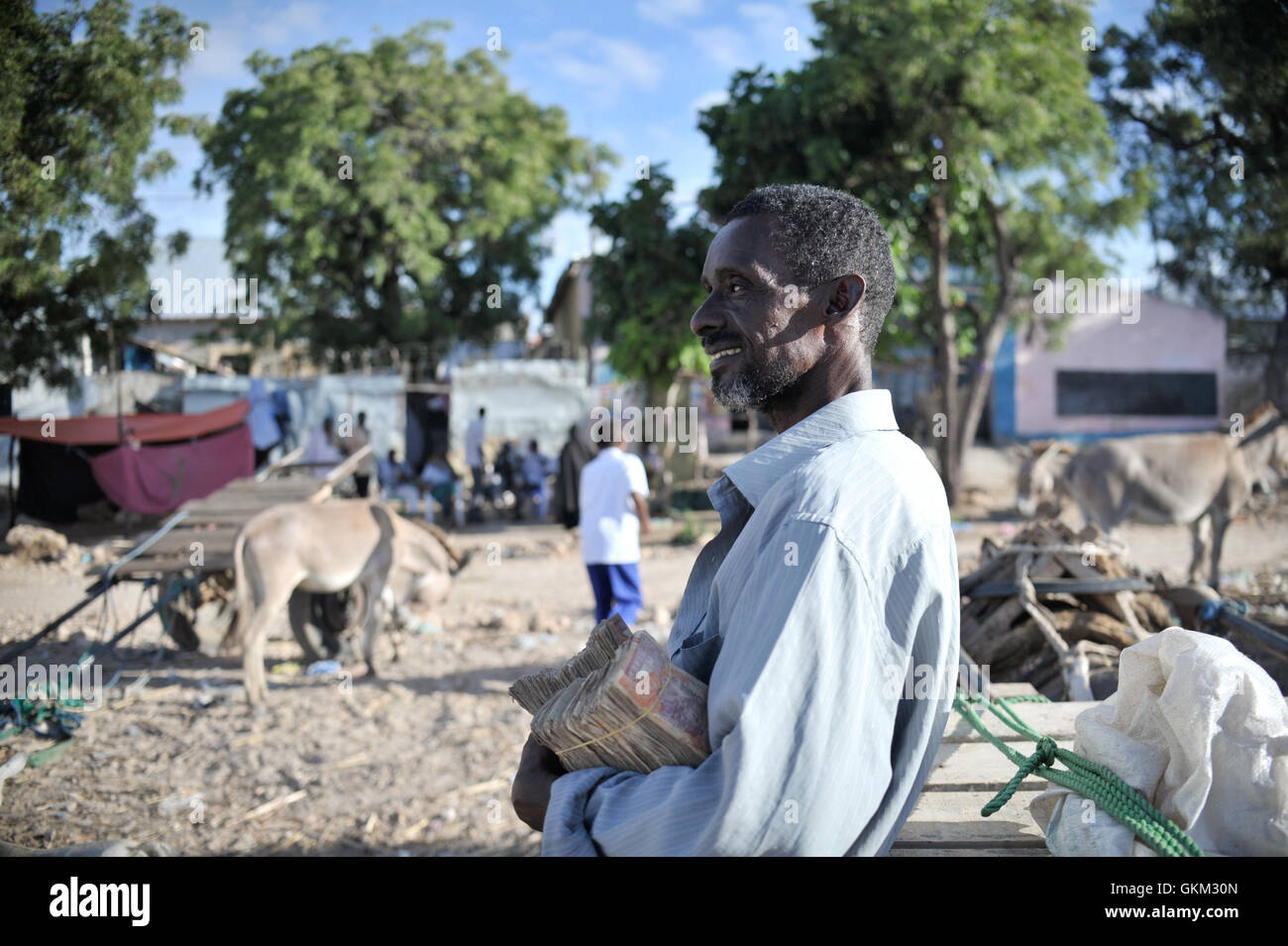 A Somali man holds the money he earned from selling goats at Bakara Animal Market in Mogadishu, Somalia, on April 13. Once notorious for being both the site of Black Hawk Down, in which 18 American soldiers were killed in 1993, and later as an al-Shabaab stronghold, Bakara market is now slowly losing its past notoriety and becoming better known for its thriving economy. In the district's animal market, thousands of goats are now brought each morning, where they are sold on to later be slaughtered for their meat. AU UN IST PHOTO / TOBIN JONES. Stock Photo