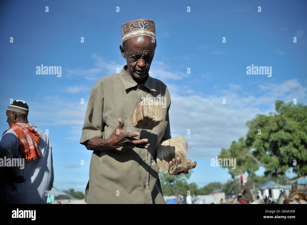 A Somali man carries the money he earned from selling goats at Bakara Animal Market in Mogadishu, Somalia, on April 13. Once notorious for being both the site of Black Hawk Down, in which 18 American soldiers were killed in 1993, and later as an al-Shabaab stronghold, Bakara market is now slowly losing its past notoriety and becoming better known for its thriving economy. In the district's animal market, thousands of goats are now brought each morning, where they are sold on to later be slaughtered for their meat. AU UN IST PHOTO / TOBIN JONES. Stock Photo