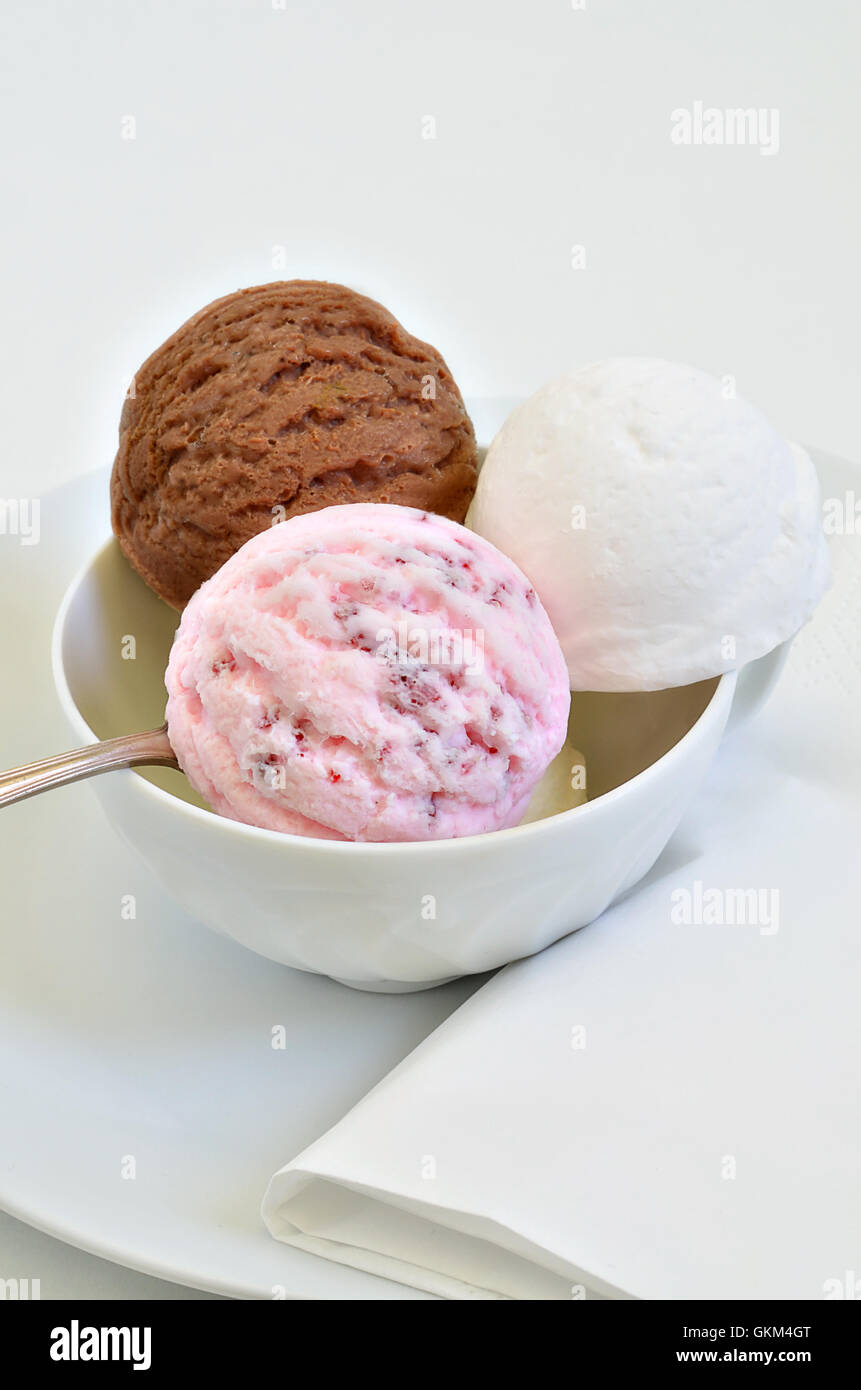 scoops of chocolate ice cream, vanilla ice cream and strawberry ice cream in a white bowl, close up, macro, vertical Stock Photo