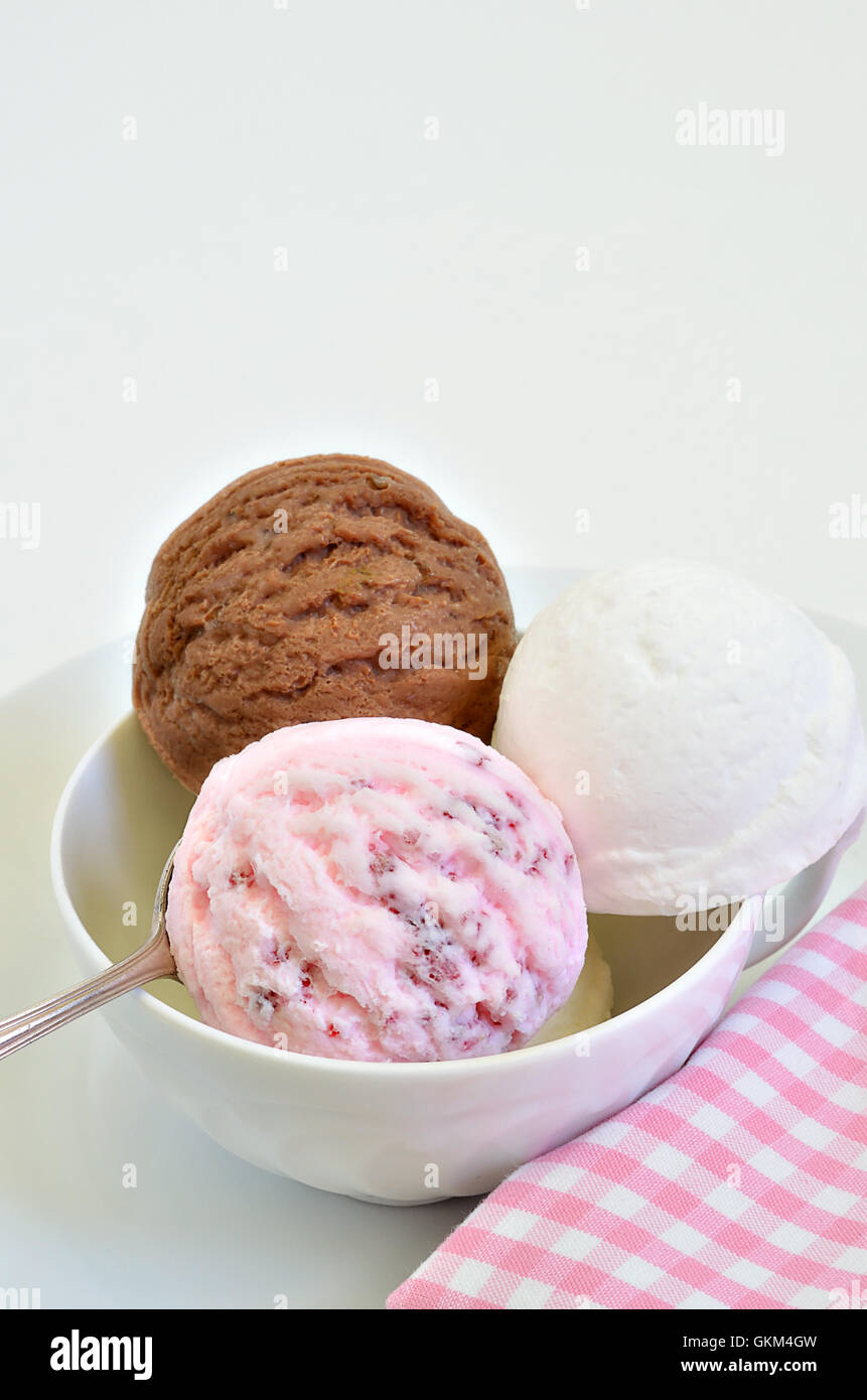 scoops of chocolate ice cream, vanilla ice cream and strawberry ice cream in a white bowl, close up, macro, vertical Stock Photo