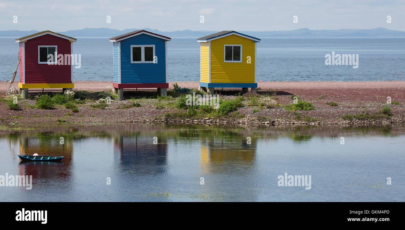 Colourfully painted cabins reflecting in a pond at Heart's Delight