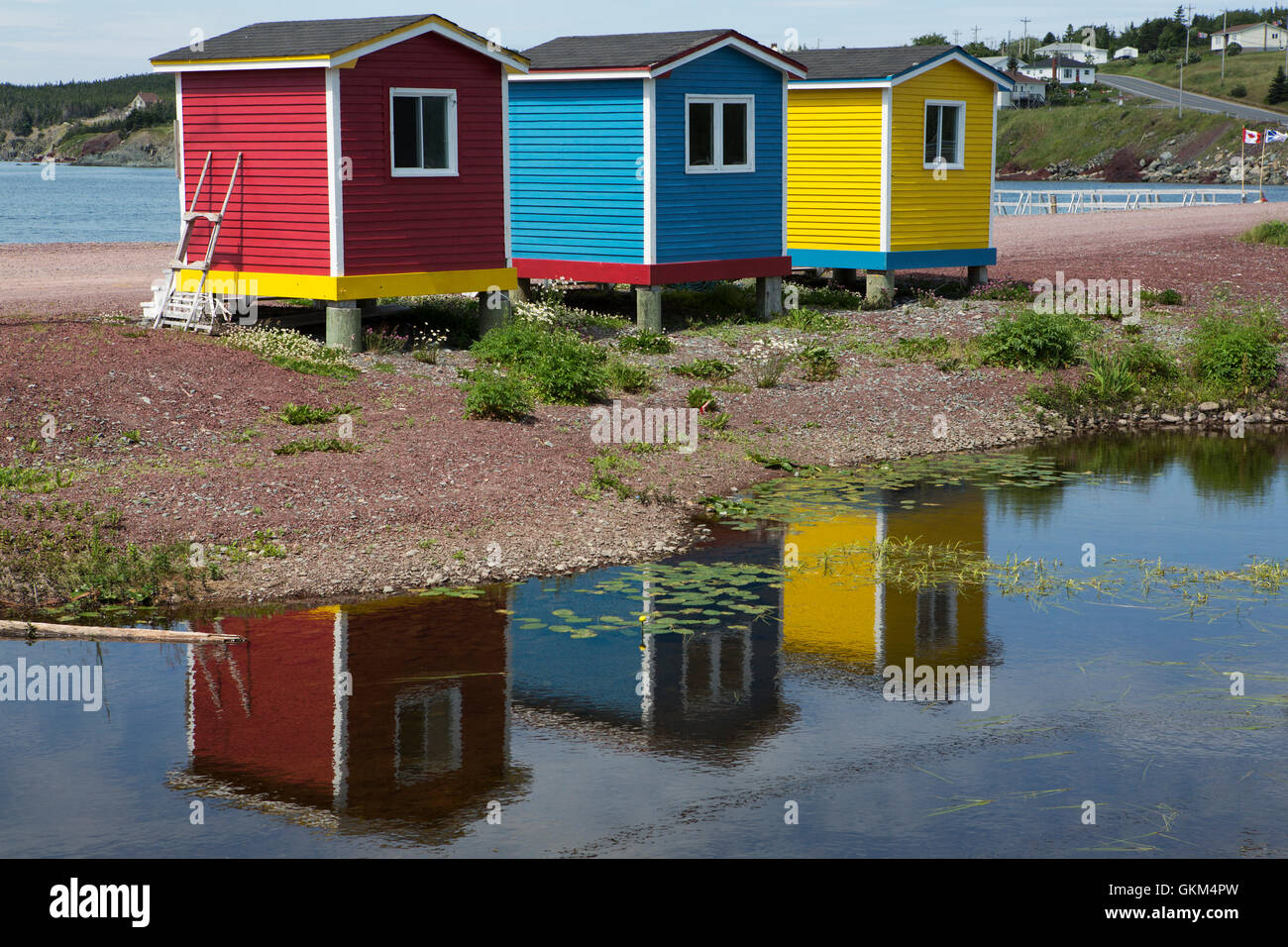Colourfully painted cabins reflecting in a pond at Heart's Delight