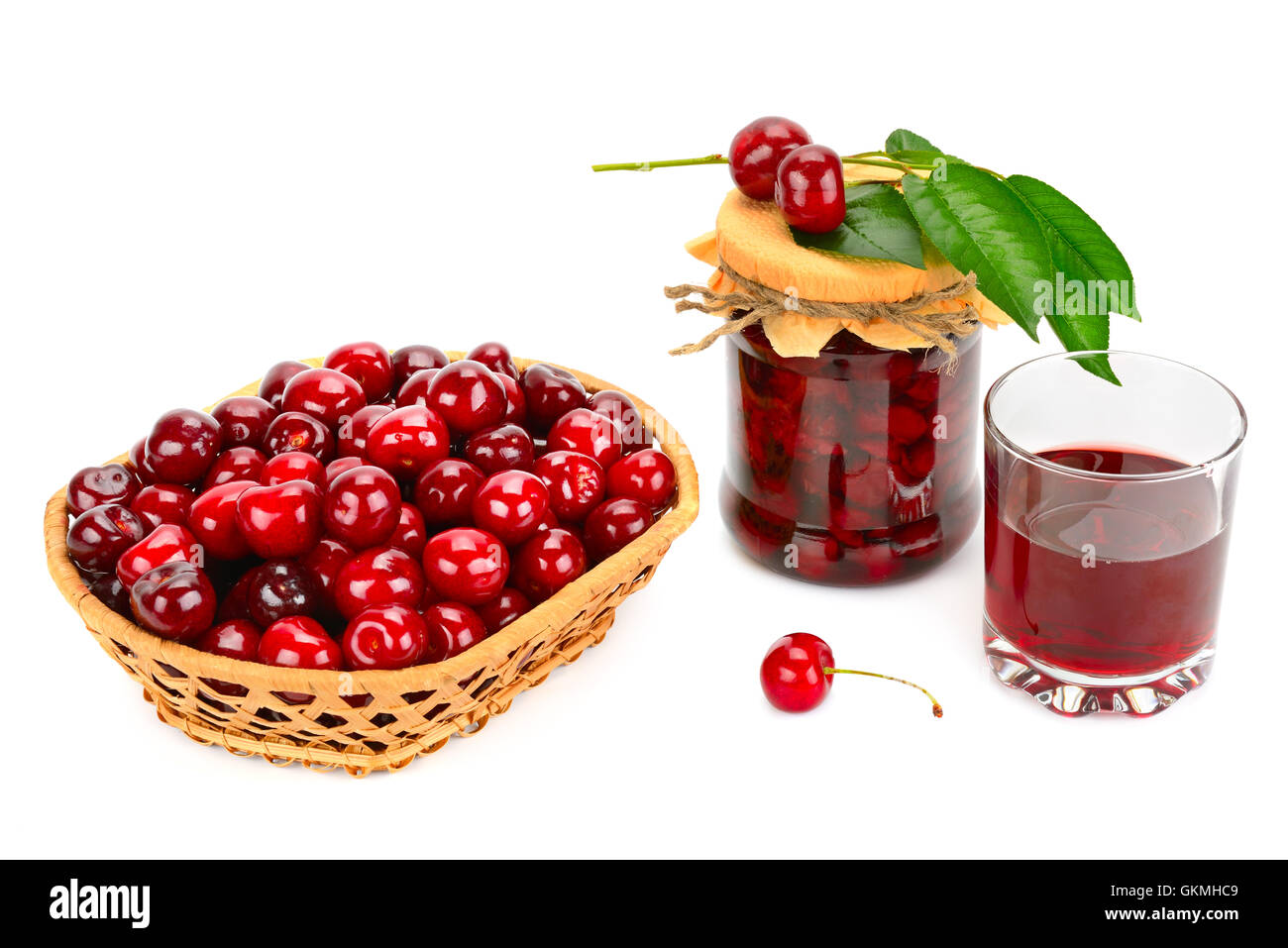 Glass of juice, basket of cherries and jar of jam isolated on white background Stock Photo
