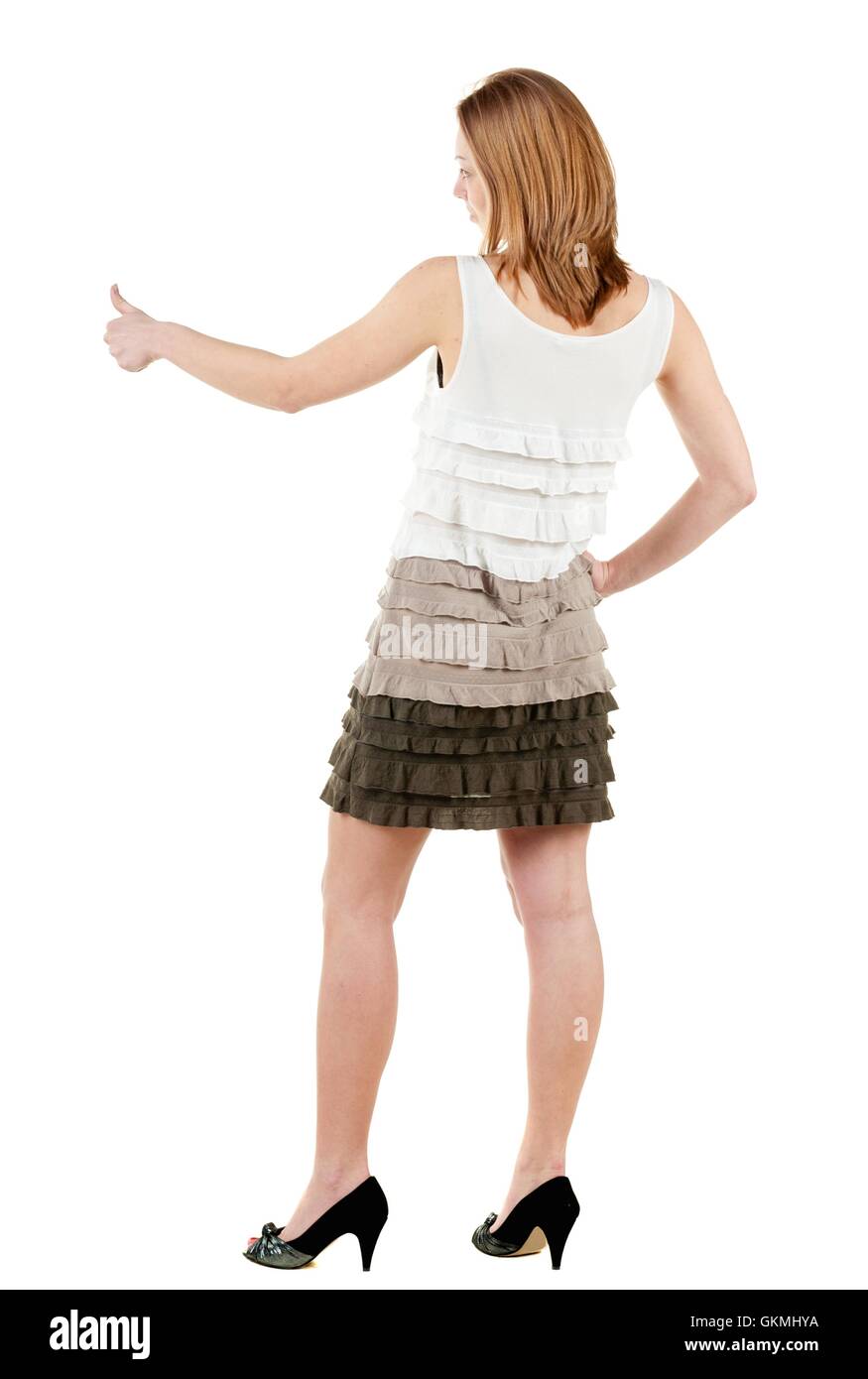 Back view of young brunette woman in dress going thumb up. Showing of positive emotions with OK sign concept . Rear view people collection. backside view of person. Isolated over white background. Stock Photo