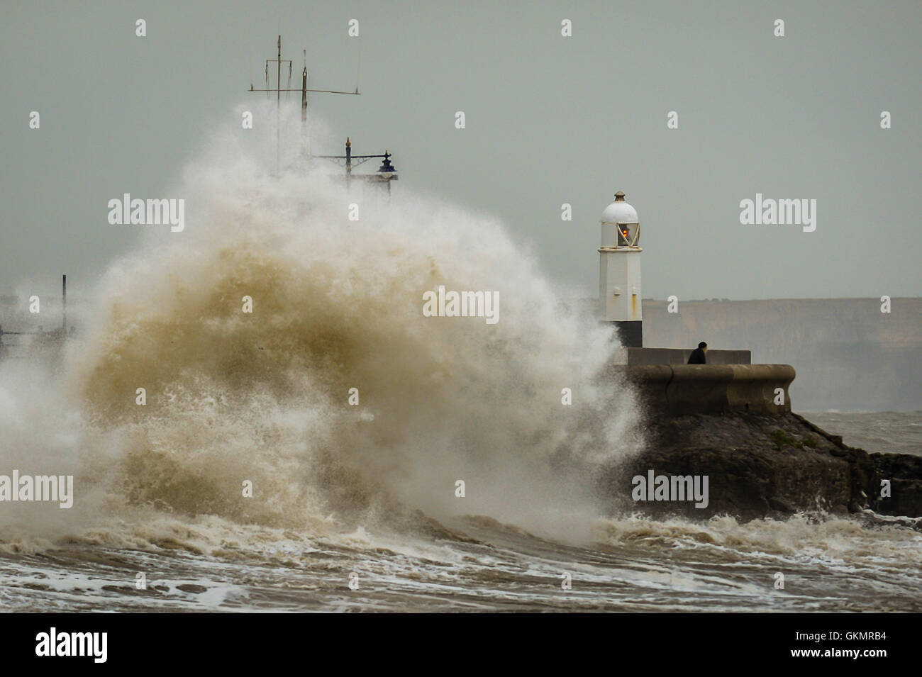 A man watches stormy conditions on the harbour wall at Porthcawl, Wales, where windy conditions and high tides are still prevalent across the UK. Stock Photo