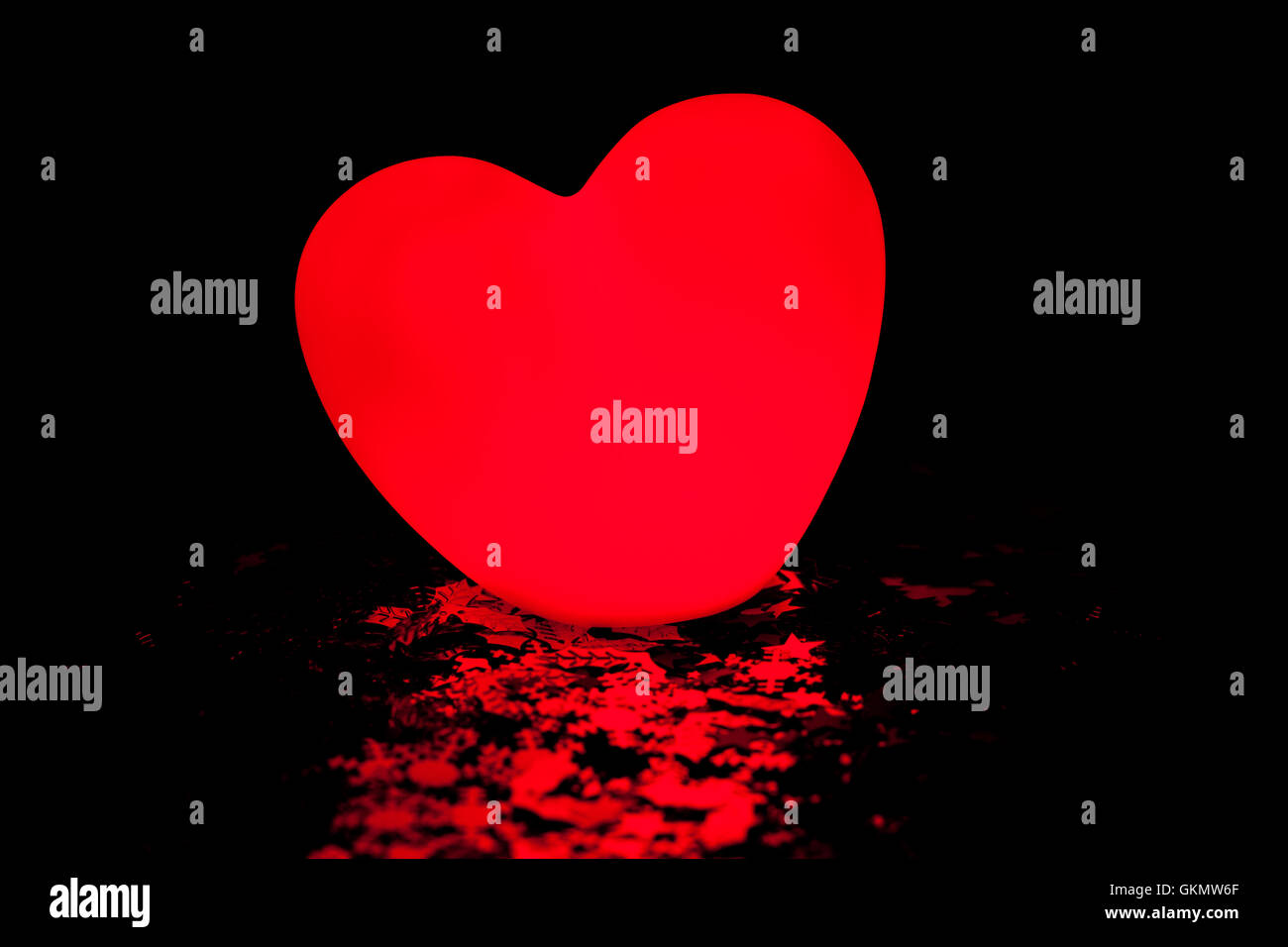 Glowing love heart on black background Stock Photo - Alamy