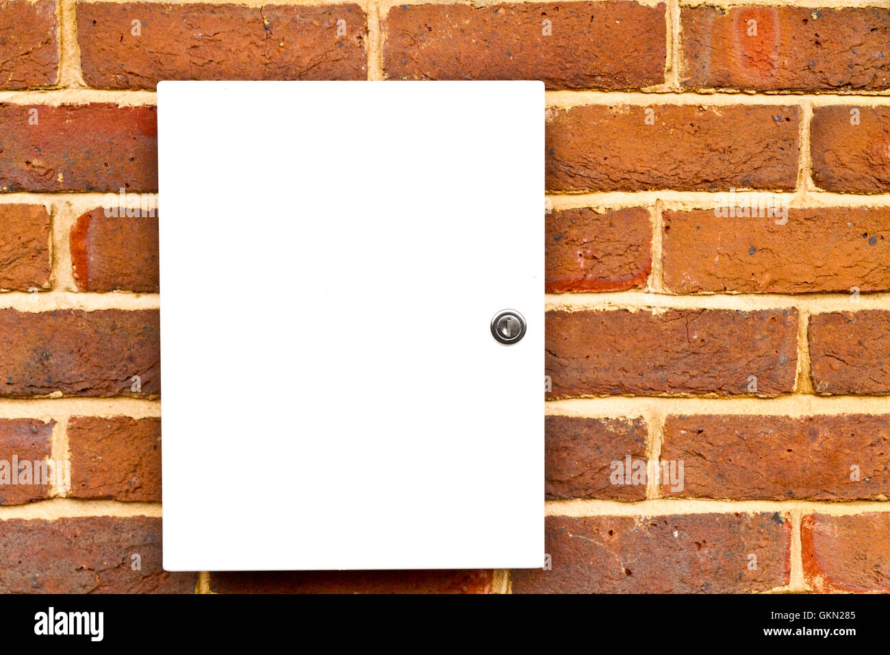 Closed locked white cupboard on a brick wall Stock Photo