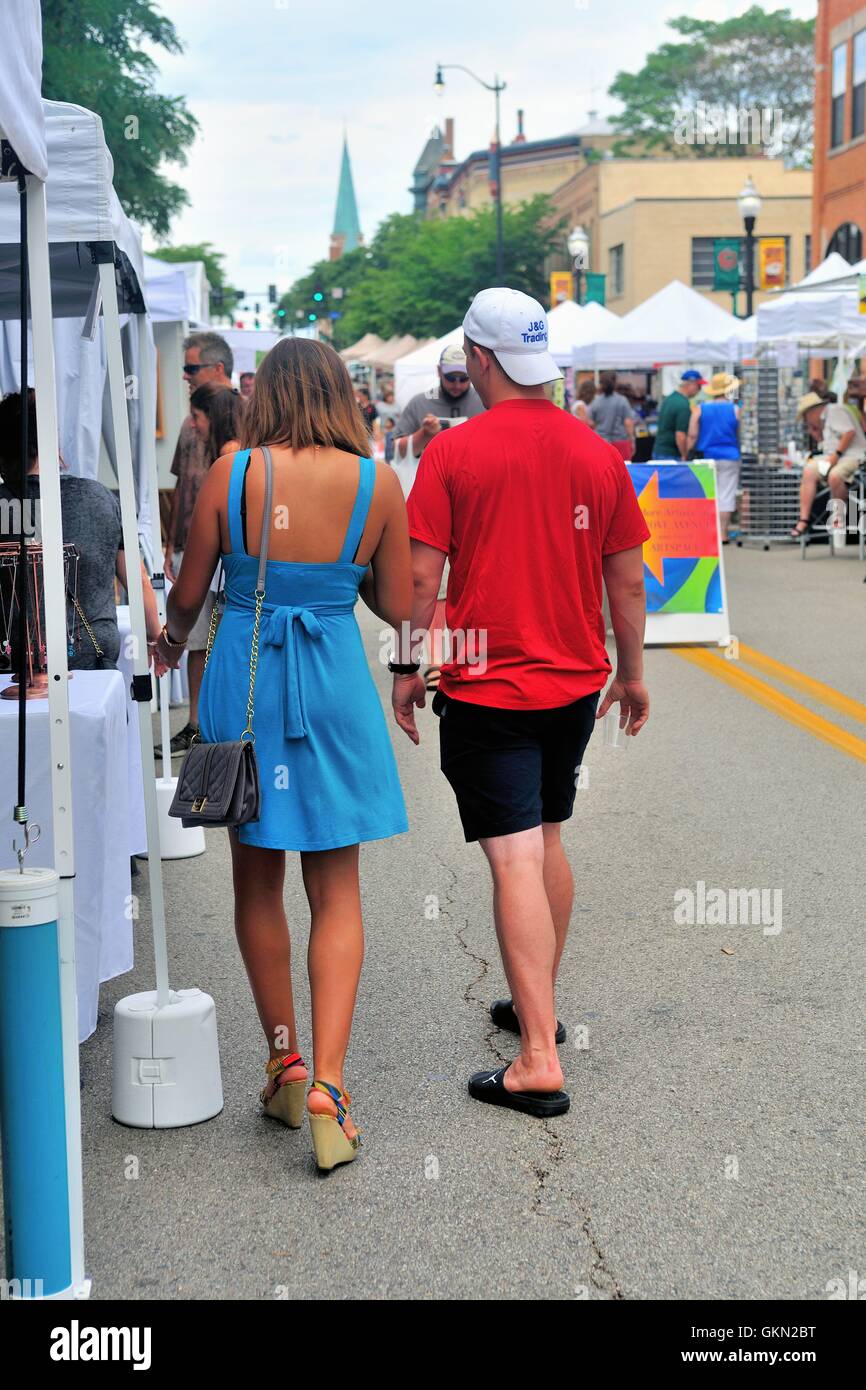 A young couple browse through booths on streets that were closed off to accommodate a street art fair. Elgin, Illinois, USA. Stock Photo