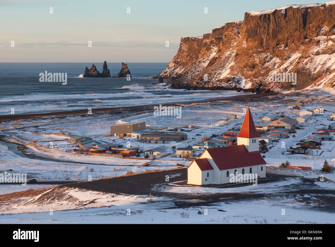 Reynisdrangar sea stacks and the Vík church at the village Vík í Mýrdal in winter, Iceland Stock Photo