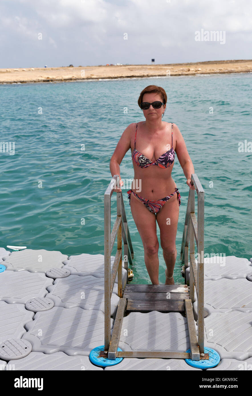 whete middle aged tanned woman swimming in the sea from floating bridge Stock Photo