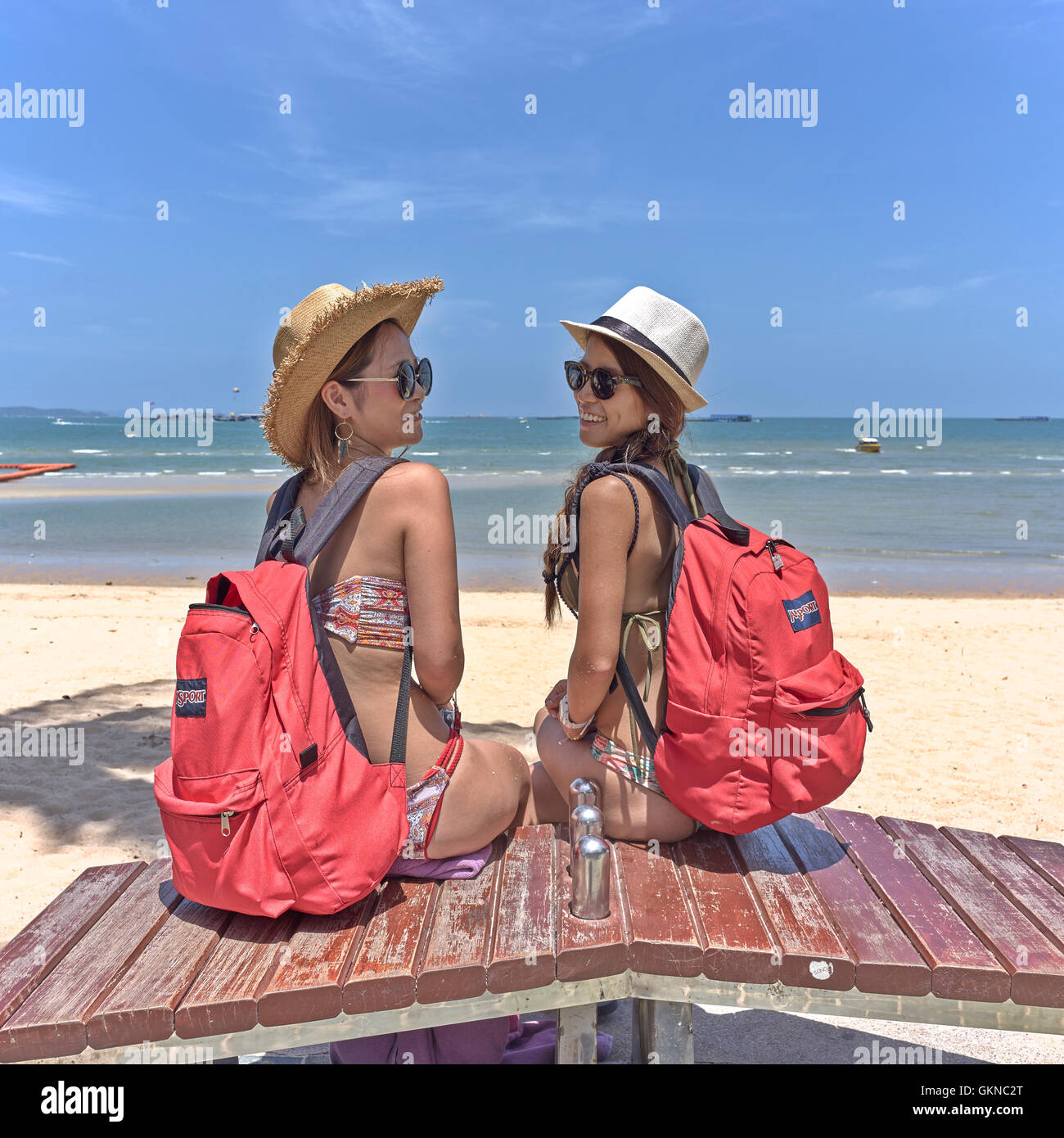Female backpacker Thailand. Two Japanese tourist women in bikinis at Pattaya beach Thailand tourism S. E. Asia Stock Photo
