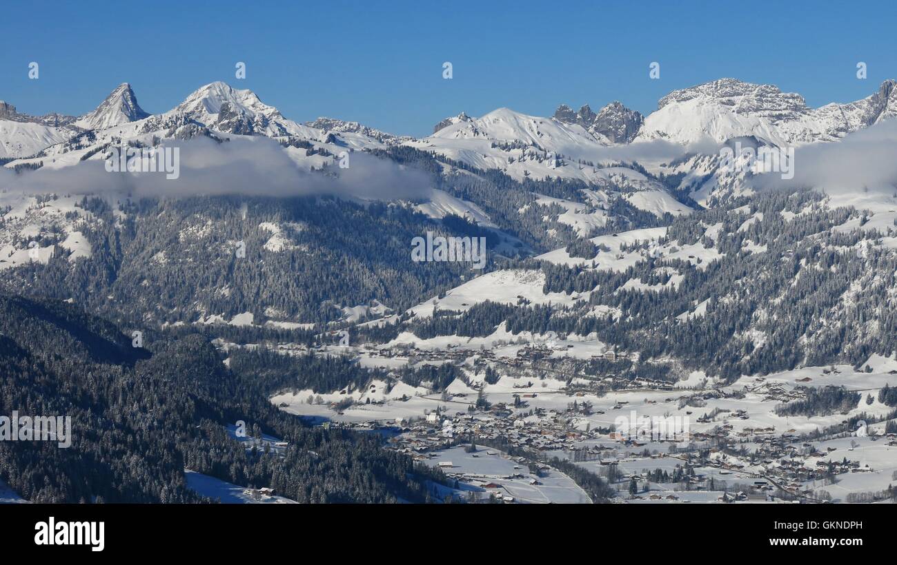 Village Saanen and snow covered mountains. Winter scene in the Swiss Alps. Stock Photo
