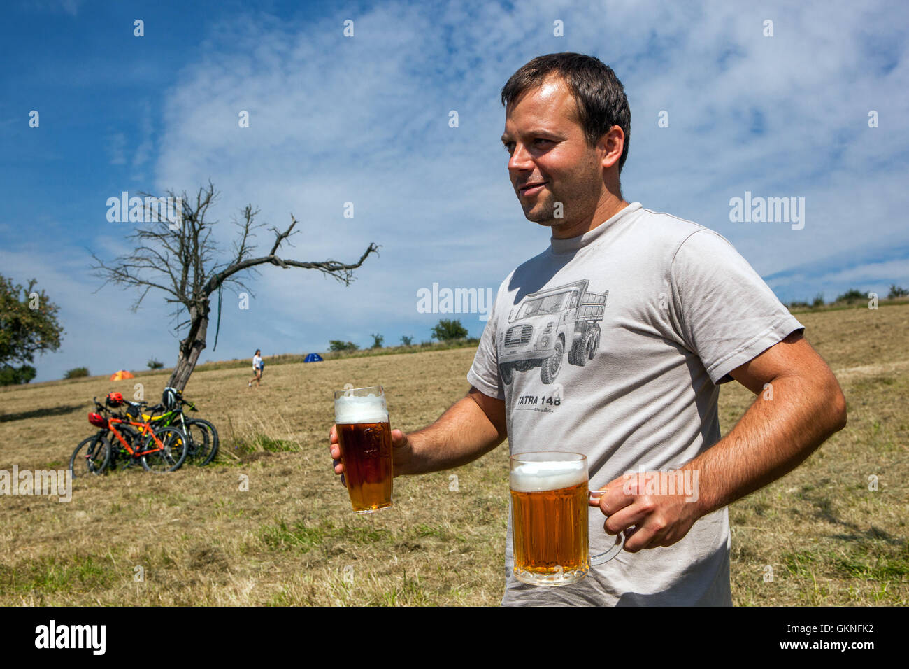 Czech man carries beers, a freshly pulled beer in glasses, Czech Republic summer calm festival outside Stock Photo