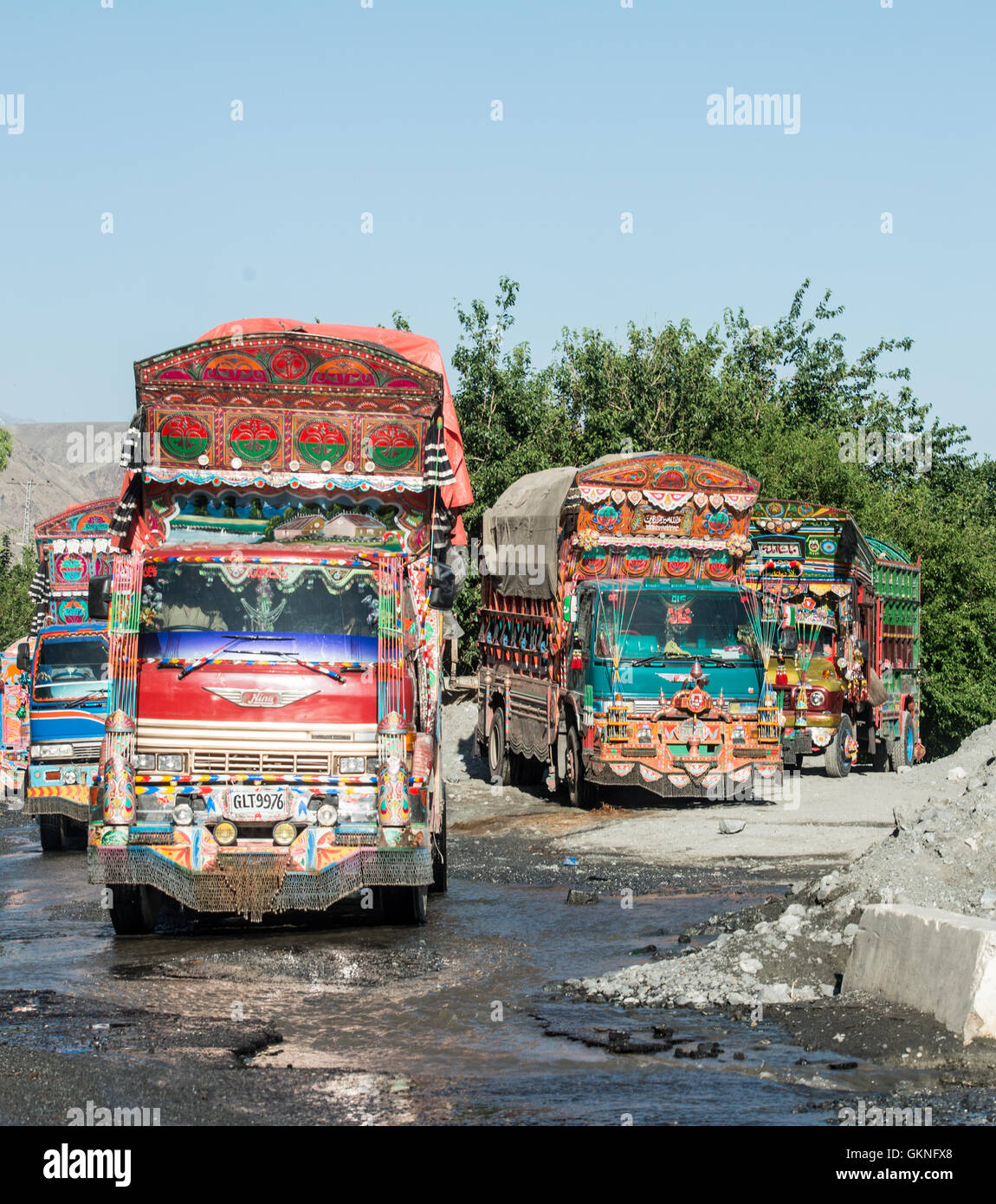 Jingly trucks crossing a ford in northern Pakistan on the Karakoram Highway south of Gilgit Stock Photo
