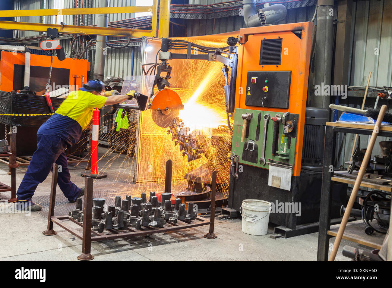 workmen in safety wear cutting, grinding metal parts for further