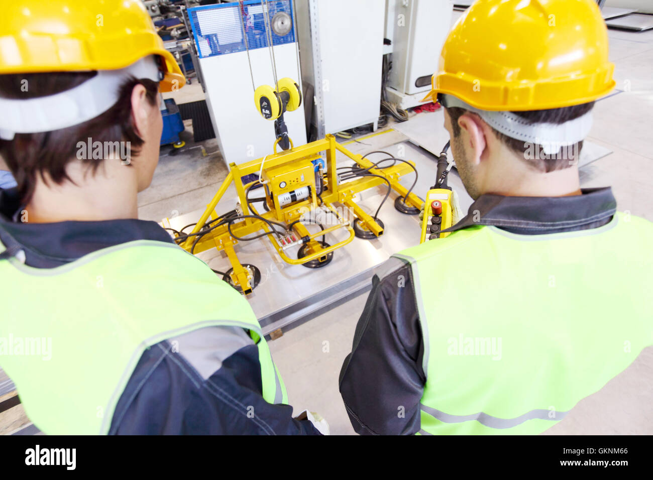 Workers near metal sheet lifting device at factory Stock Photo - Alamy