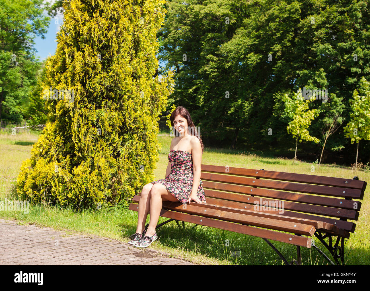 young beautiful smiling woman girl sitting on a park bench on sunny ...