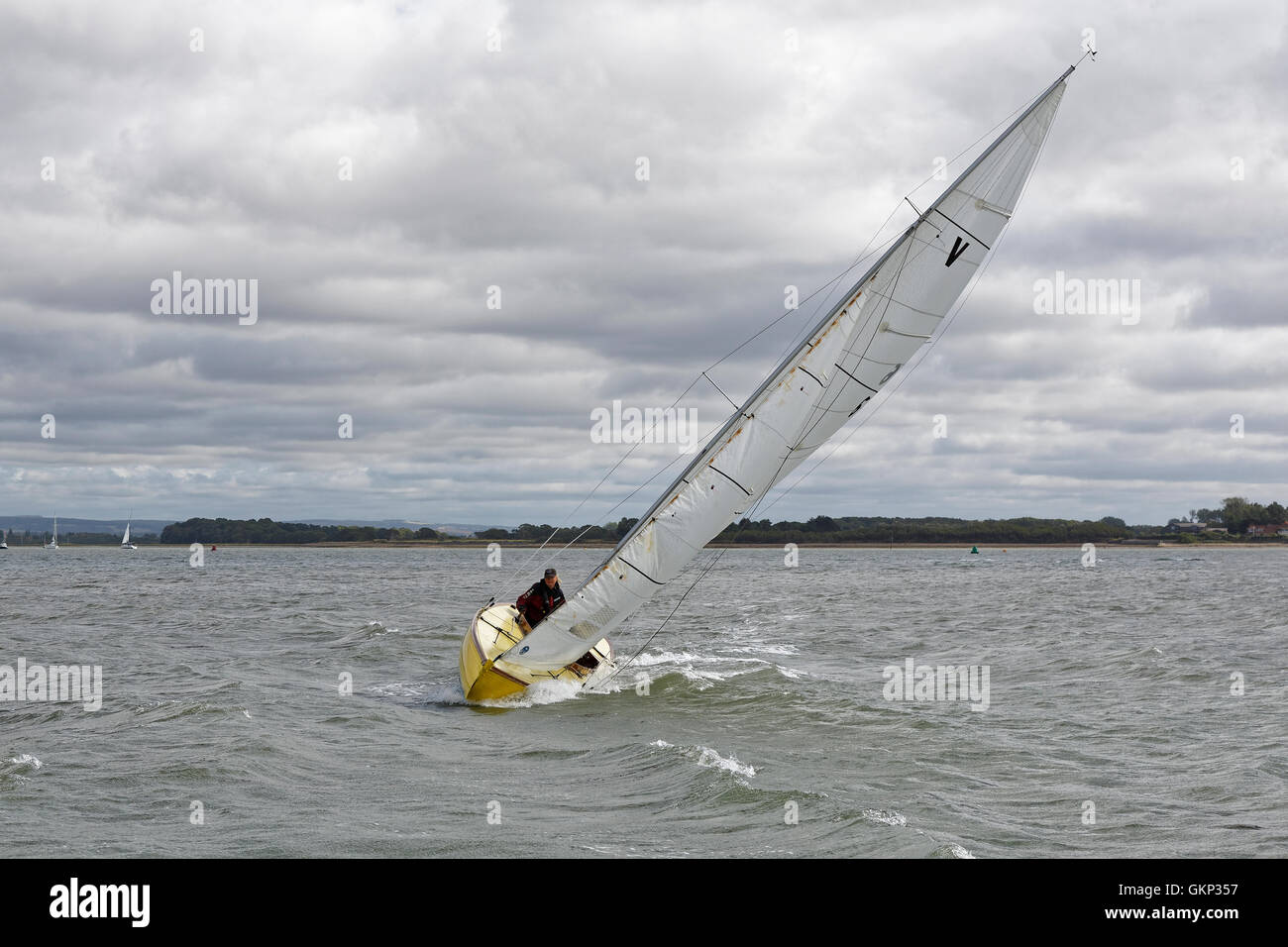 A sailing boat heels over, decks awash and running fast driven by strong winds. Stock Photo