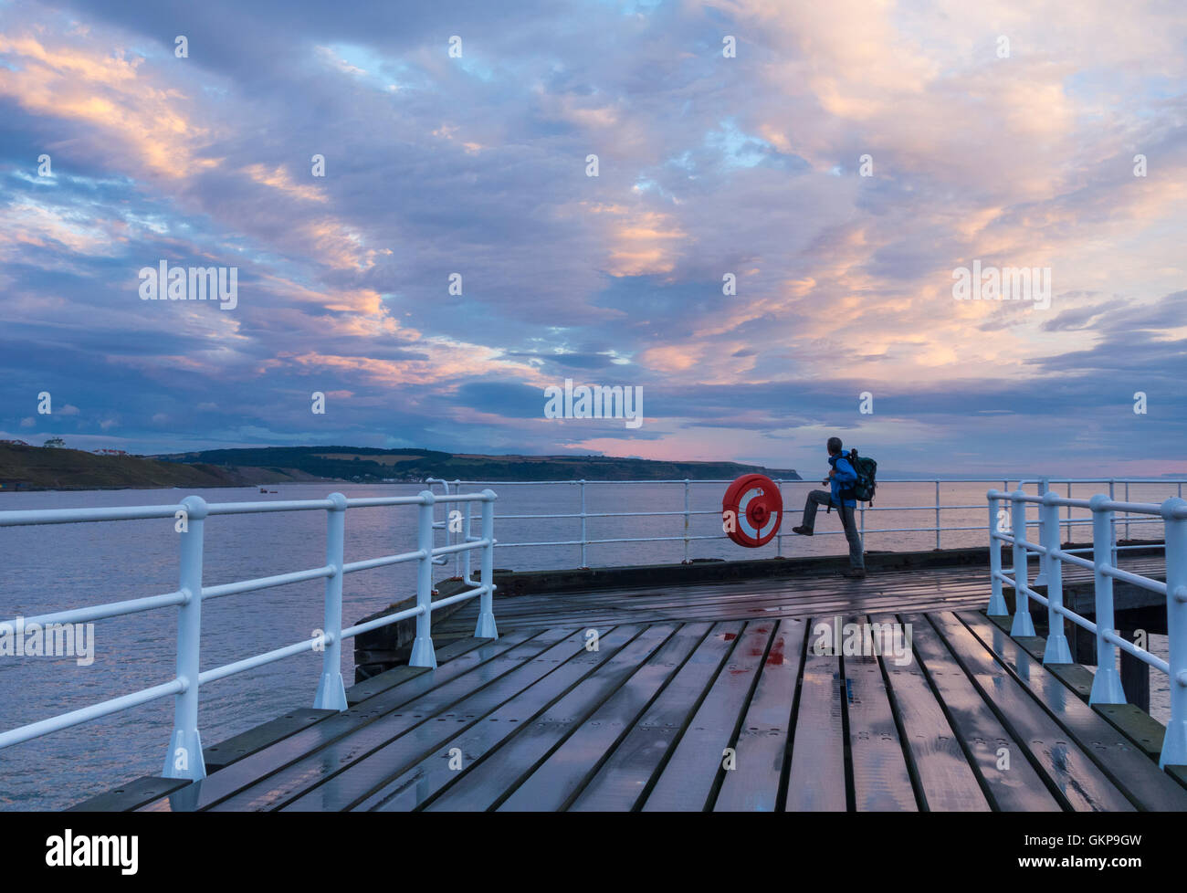 Whitby, North Yorkshire, England, UK. 22nd Aug, 2016. Weather: A hiker on Whitby pier at sunrise as the sky clears and lenticular clouds fill the sky between bands of rain early Monday morning. Credit:  Alan Dawson News/Alamy Live News Stock Photo