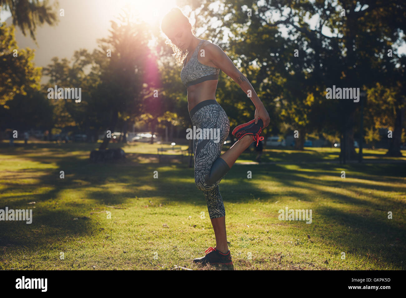 Full length portrait of healthy young woman working out in a park. Sportswoman warming up before training session outdoors on a Stock Photo