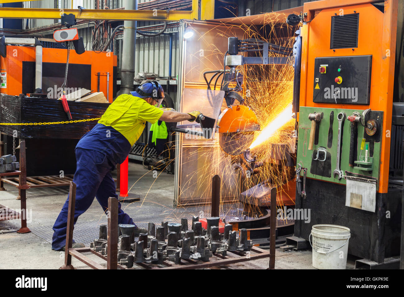 workman grinding and cutting away cast metal components from its