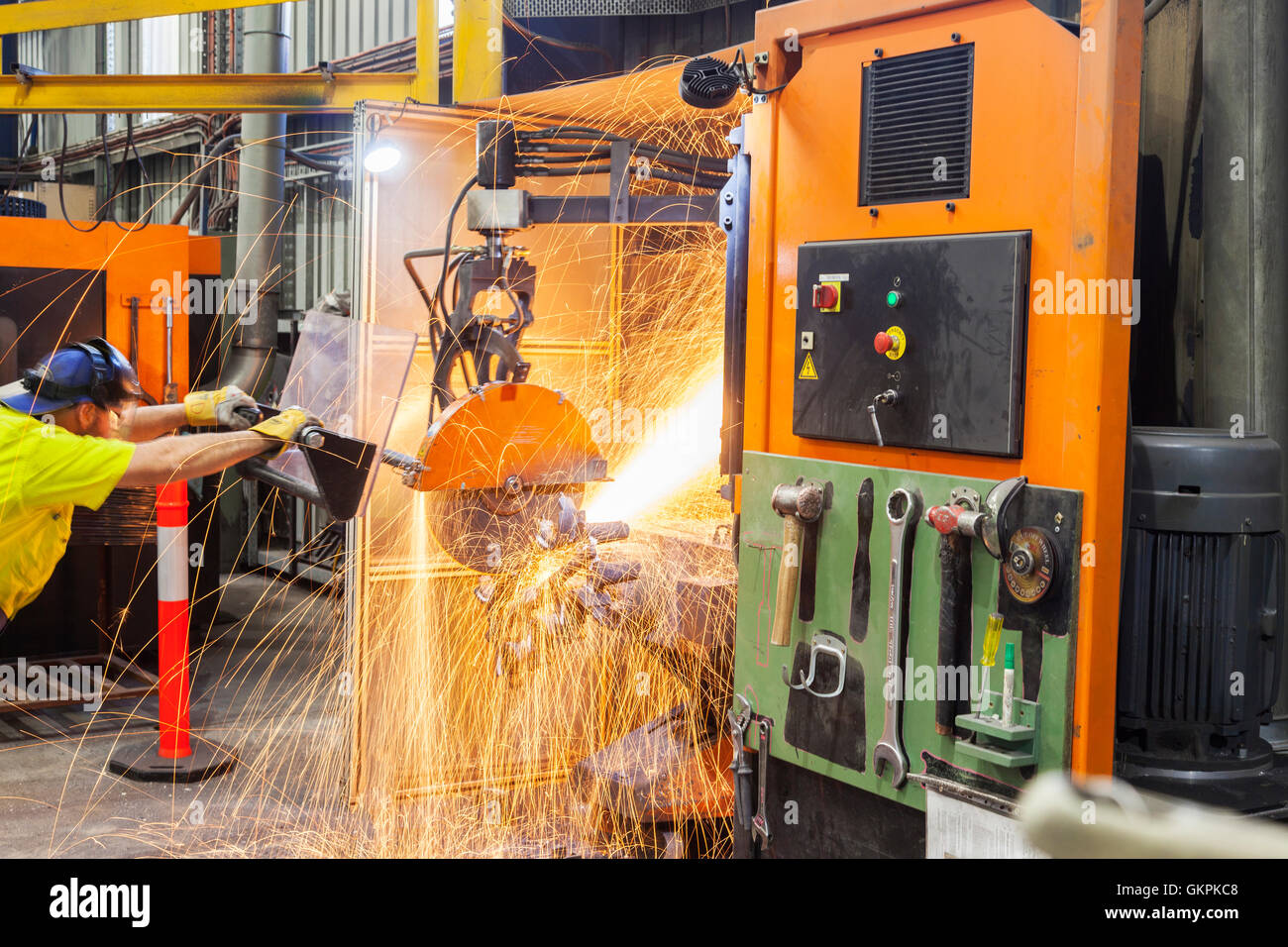 workman grinding and cutting away cast metal components from its