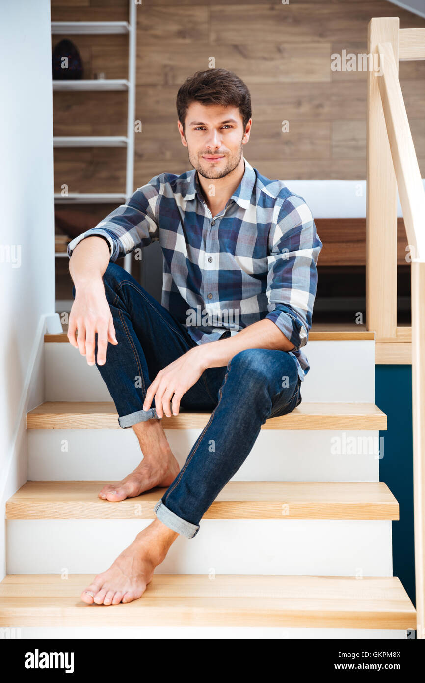 Portrait of a young handsome man sitting on the staircase at home Stock ...