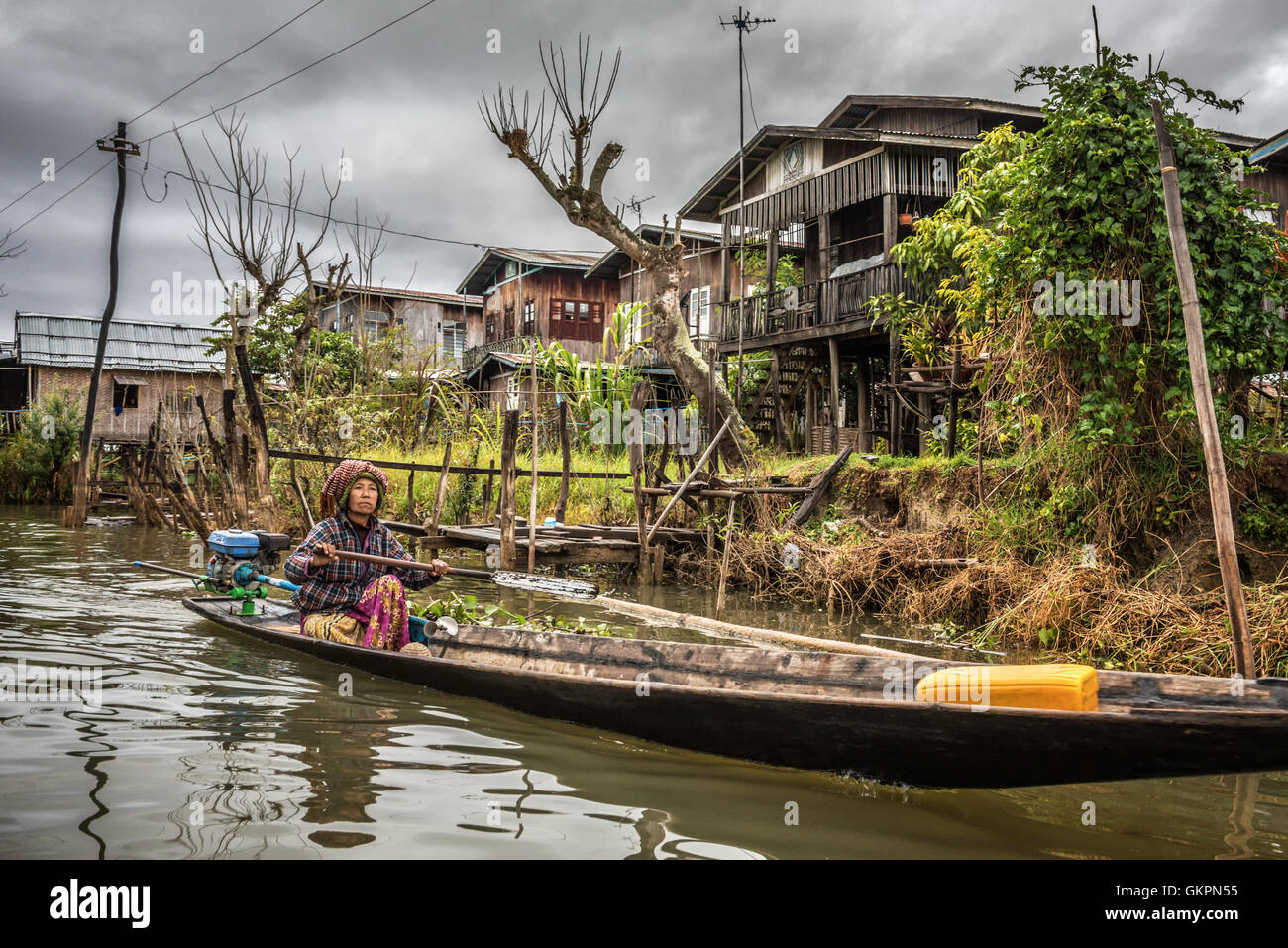 Woman of the Inthar tribe  boating through her village.  Inthar people build wooden houses on piles to live on the lake. Stock Photo