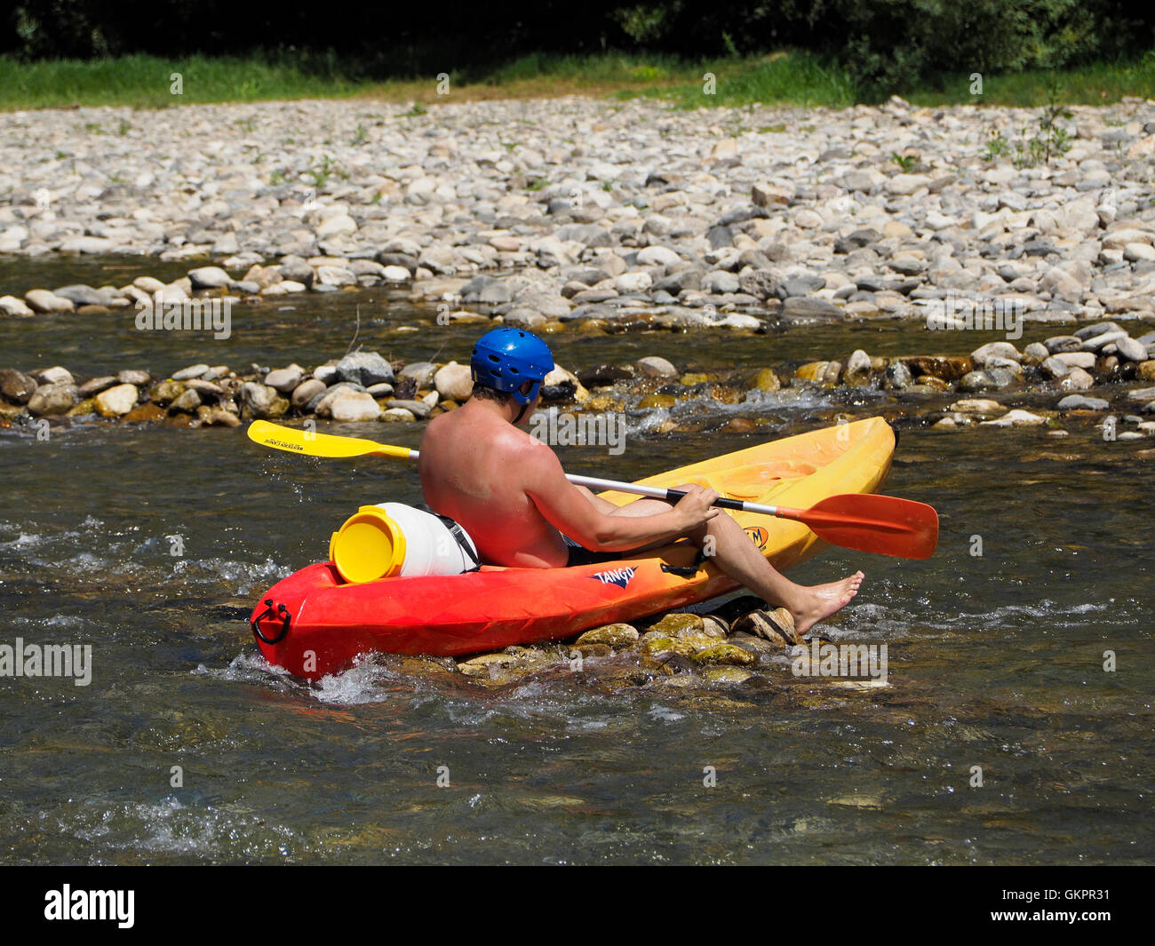 Making a canoe trip is a very popular activity in France, this is man is running into a typical problem on the Herault river. Stock Photo
