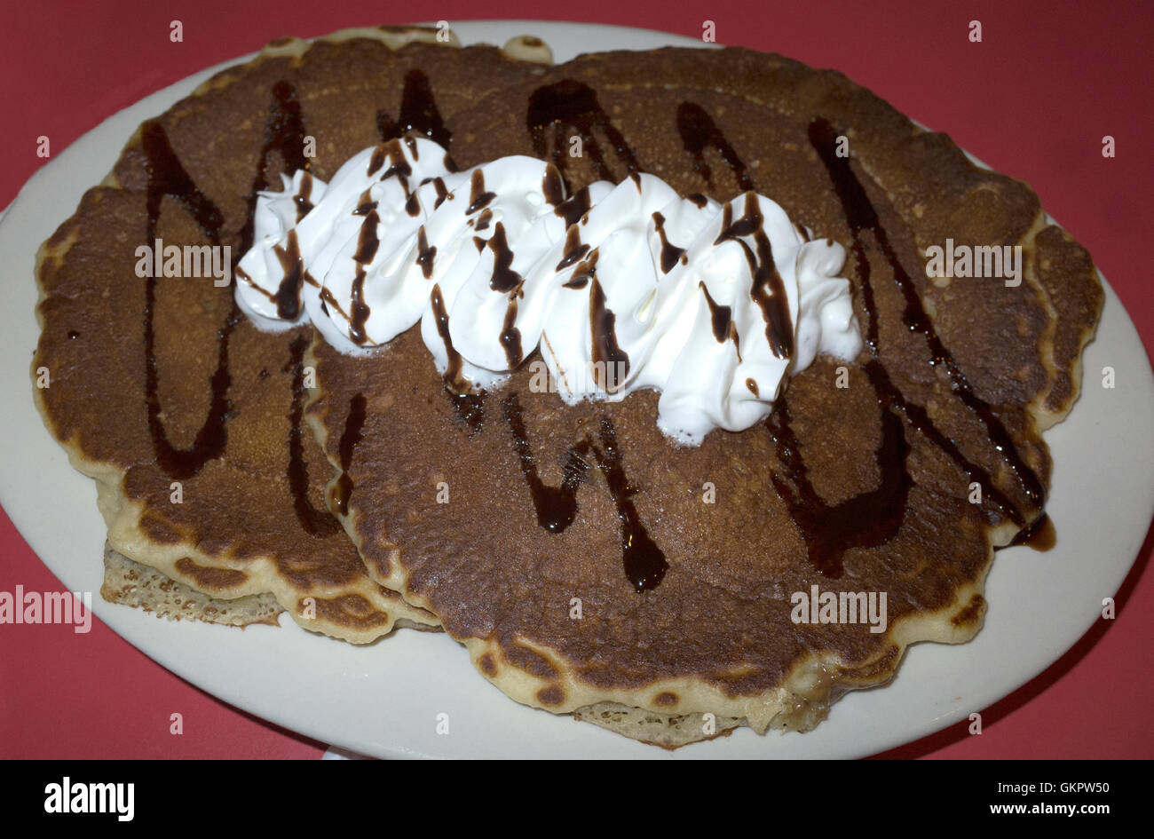 Restaurant serving of delicious pancakes topped with whip cream and stripes of chocolate. St