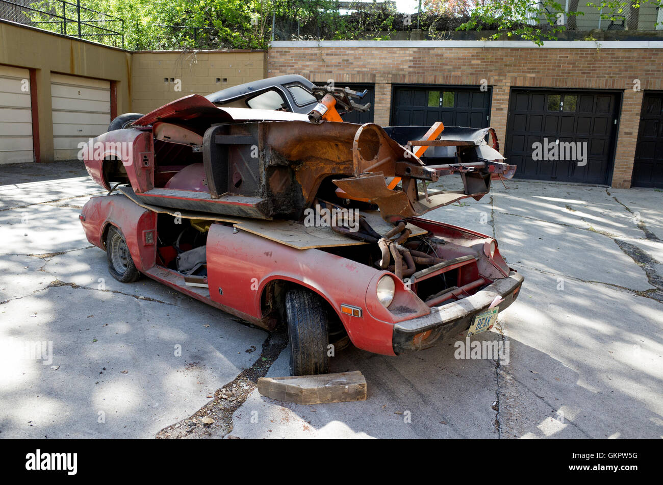 Two frames of old cars piled on top of each other evicted from the apartment garage. St Paul Minnesota MN USA Stock Photo
