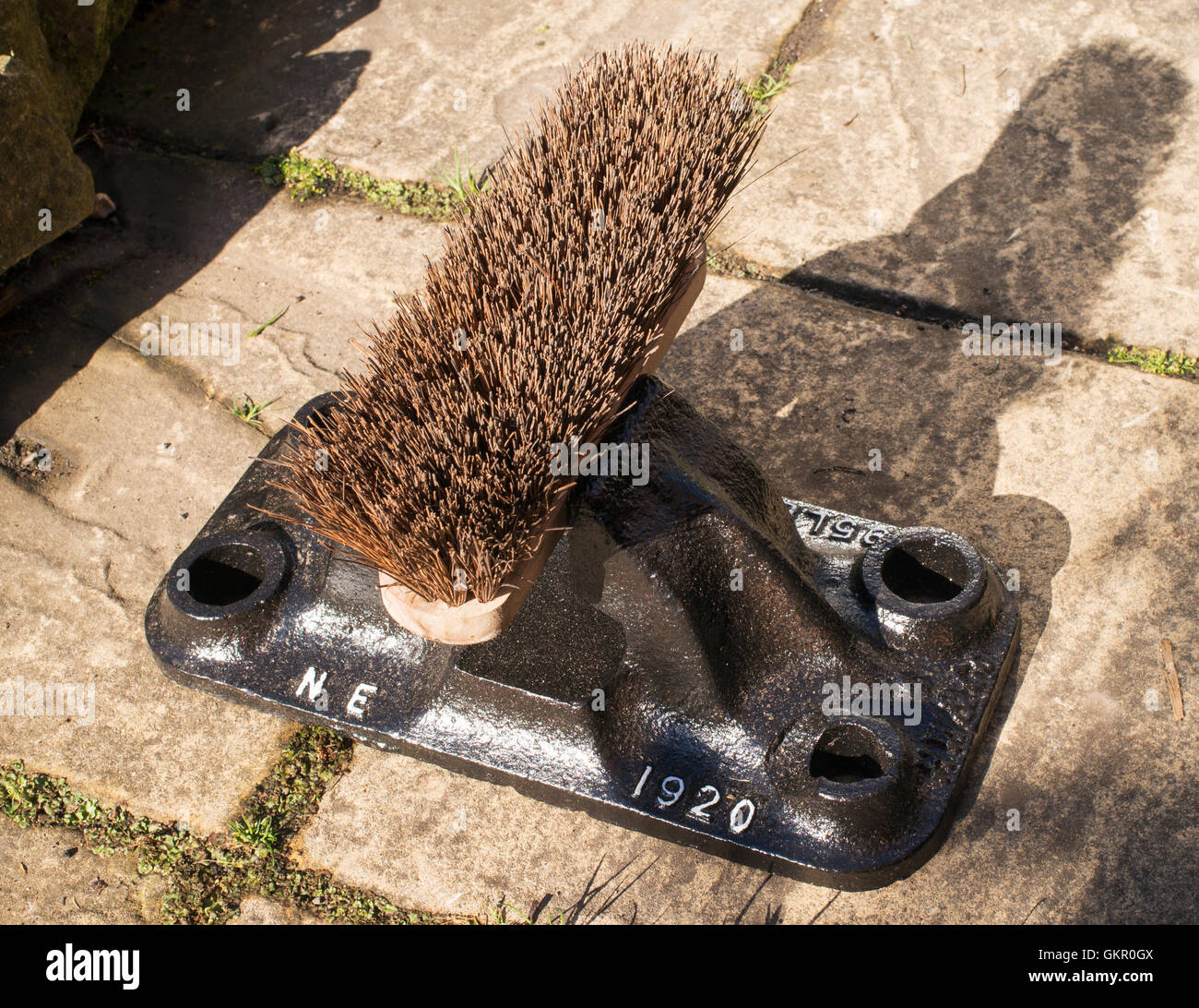 An old railway track chair used to hold a broom head as a boot cleaner, England UK Stock Photo
