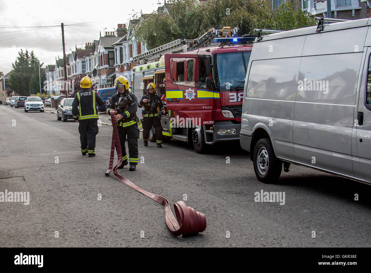 Firefighters setting up a water supply from a hydrant during a fire at