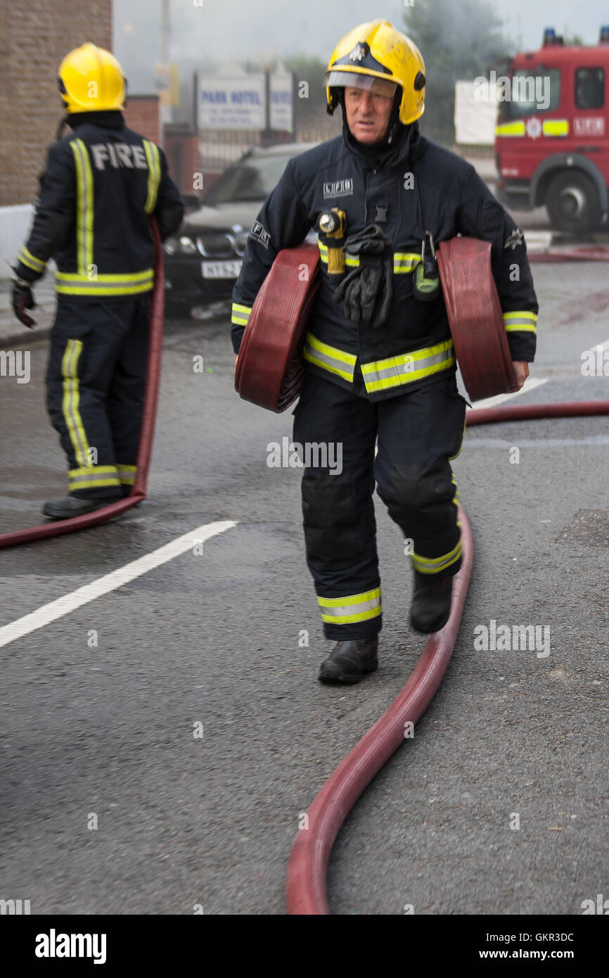 Firefighter carrying hoses during a fire at a hotel in East London Stock Photo