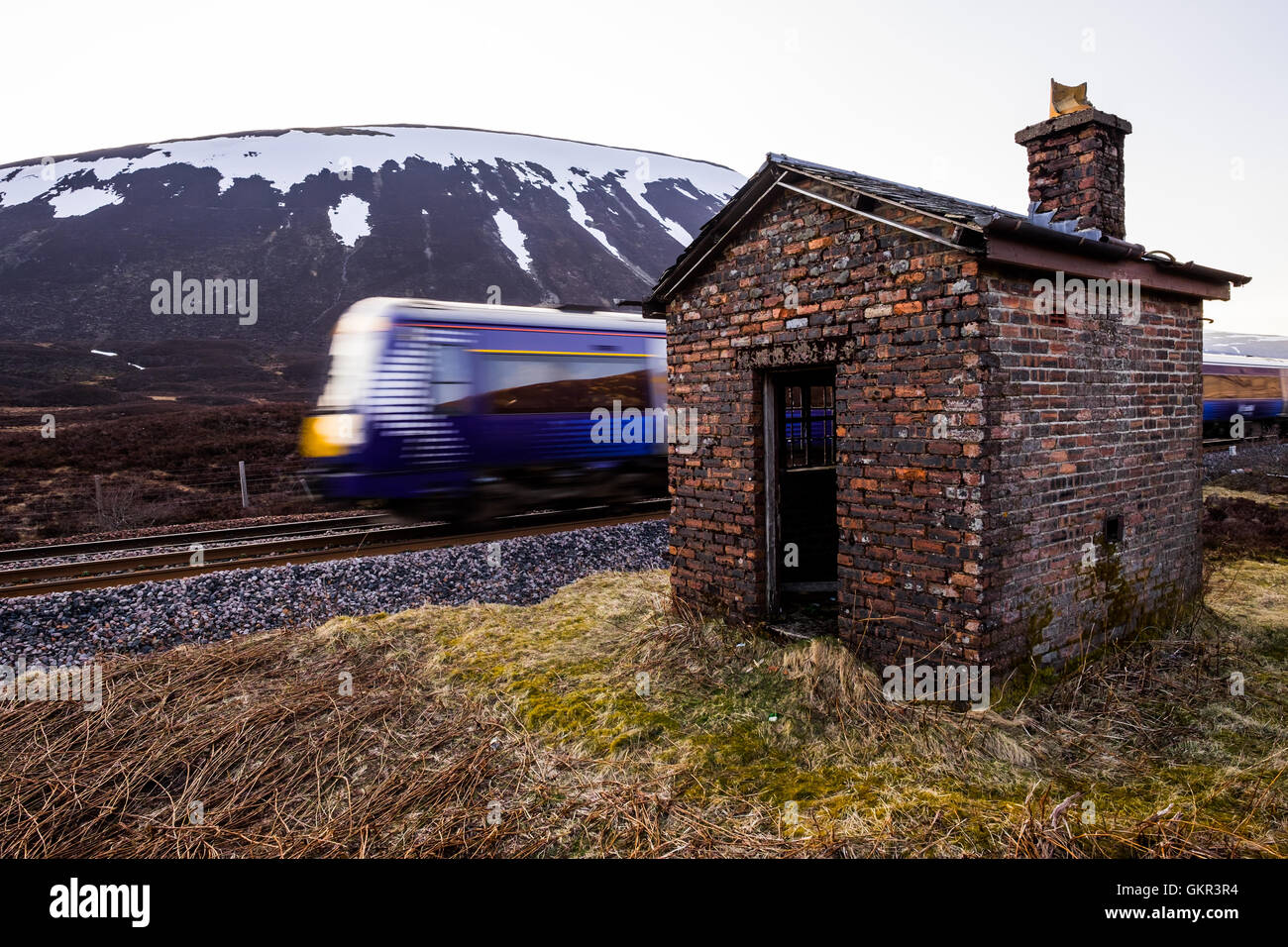 A commuter train passes a disused railway signal box at Druimuachdar (Drumochter) Pass. Stock Photo