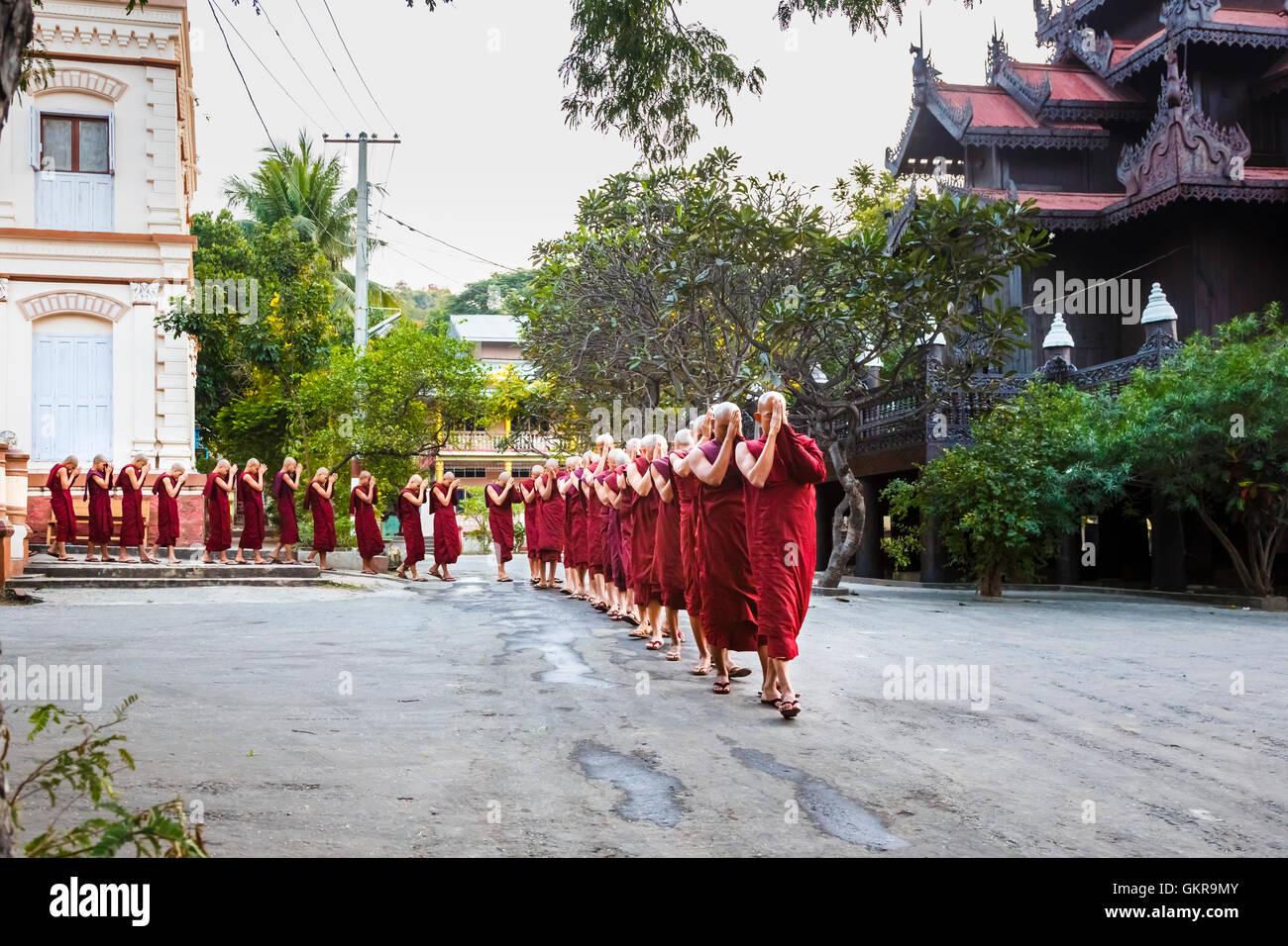 Buddhist monks at an evening prayer ceremony entering Shwe Kyin Monastery at the foot of