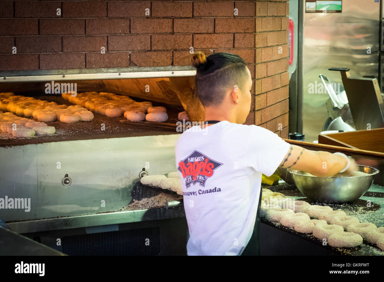 A worker makes authentic Montreal-style bagels at Siegel's Bagels at Granville Island Public Market in Vancouver, Canada. Stock Photo
