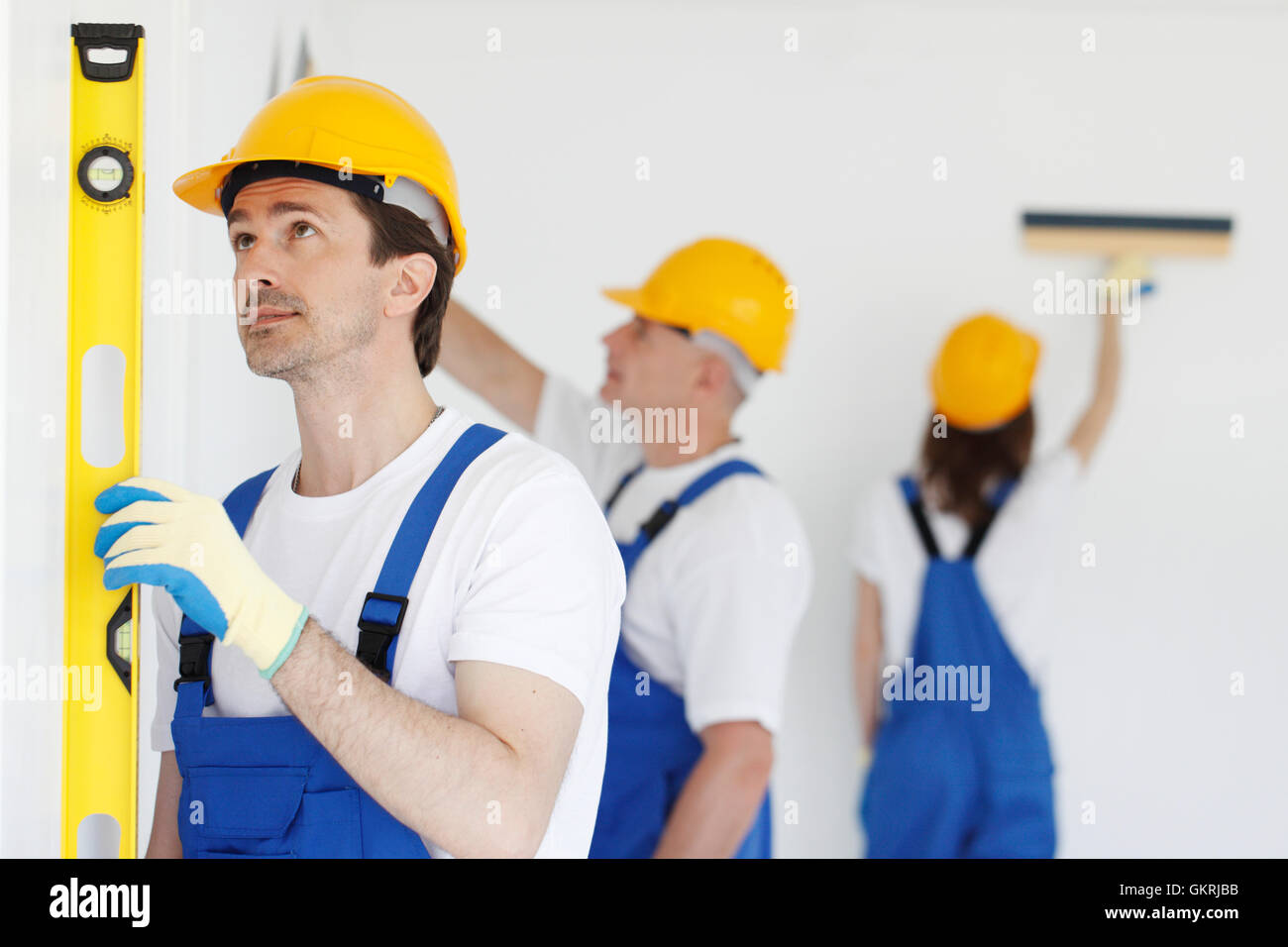 Building teamwork concept - group of smiling builders in hardhats with tools indoors Stock Photo