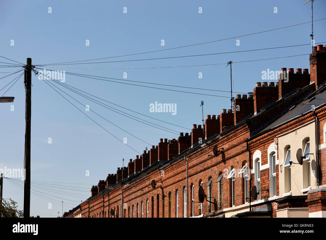 overhead telephone lines from wooden telegraph pole distribution point to victorian terraced houses Stock Photo