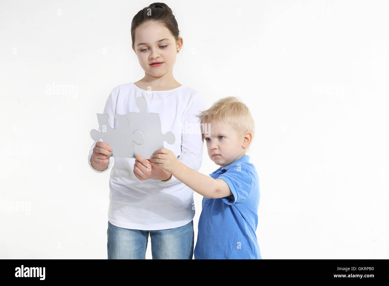 Sister and brother play with puzzle pieces isolated on white Stock