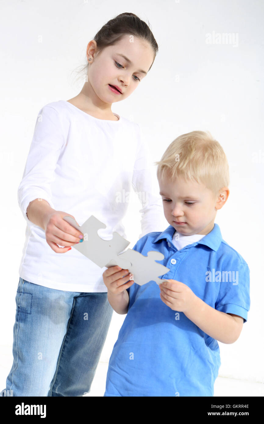 Sister and brother play with puzzle pieces isolated on white Stock